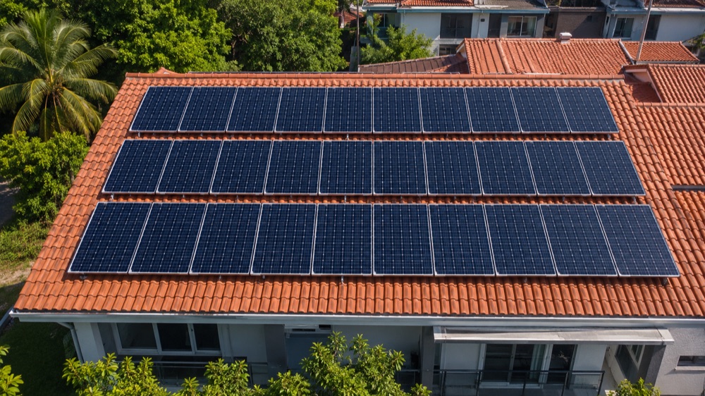 Aerial drone view of rows of solar panels installed on the red clay-tile roof of a Malaysian terrace house in Selangor under the Solar ATAP programme. This is the type of residential rooftop solar installation eligible for the SuRIA Home RM 3,000 rebate.
